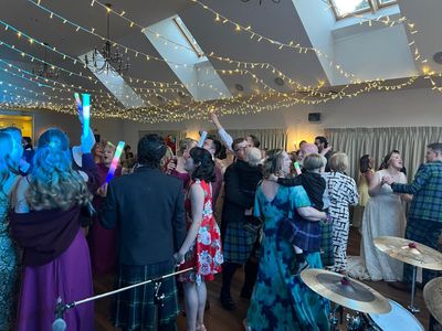 A full dancefloor mid-ceilidh beneath a canopy of fairy lights