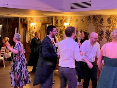 Wedding guests in their finery dancing in an elegant candlelit room
